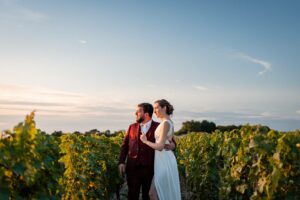 Les mariés marchent dans les vignes du Château Smith Haut Lafitte au coucher du soleil