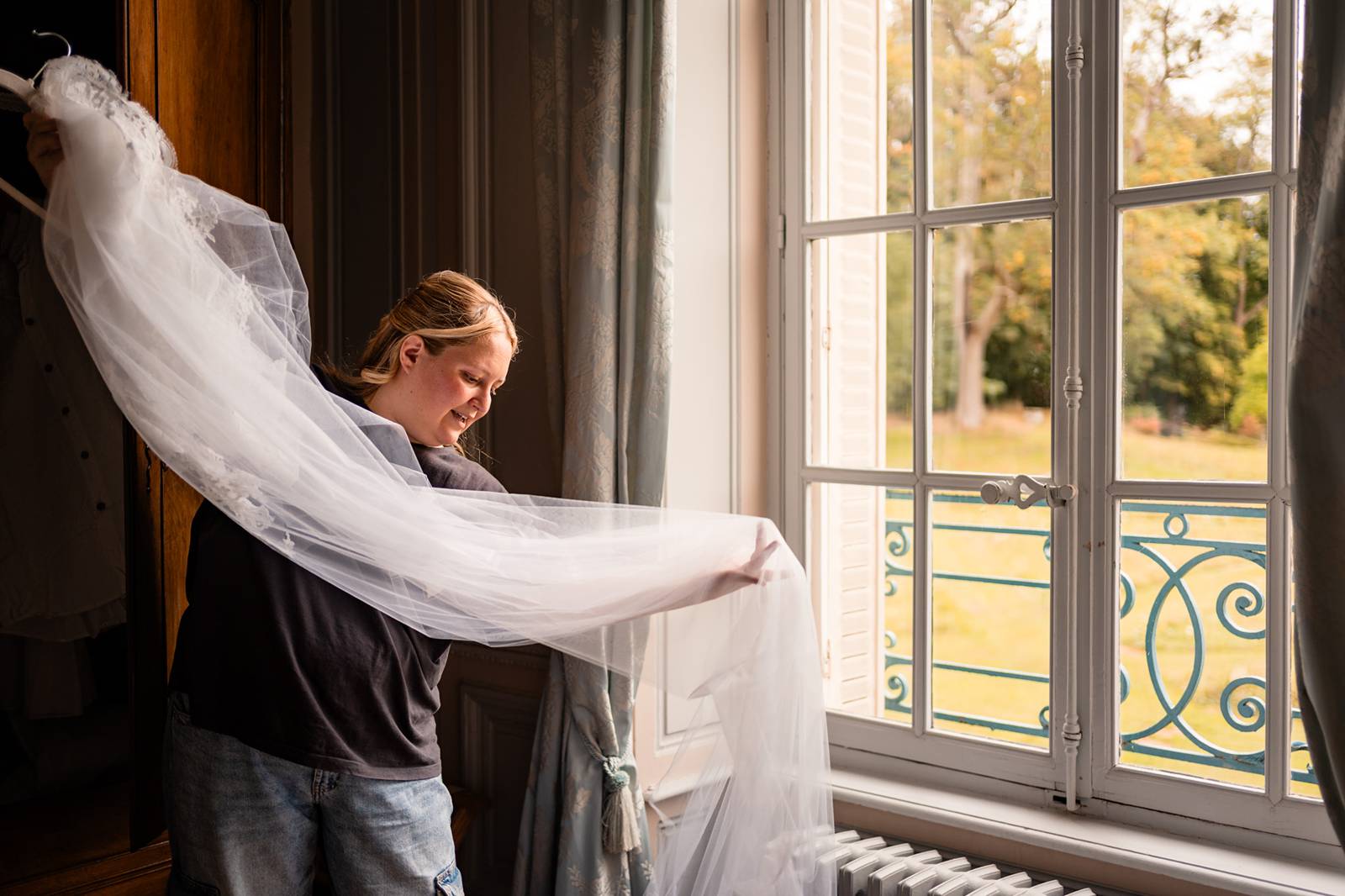Robe de mariée suspendue dans une chambre lumineuse du château