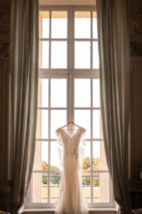 Robe de mariée suspendue dans une chambre lumineuse du château